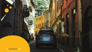 Auto recorriendo una calle estrecha con fachadas coloridas en la Toscana.