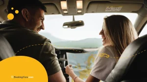 Pareja sonriendo dentro del auto mientras miran un mapa.