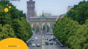 Vista frontal de la Puerta de Brandeburgo rodeada de árboles y tráfico urbano.