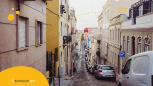 Calle empinada y adoquinada en Lisboa con autos estacionados y edificios antiguos.
